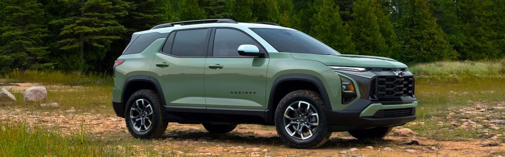 A sage green Chevrolet Equinox SUV parked on a rocky trail with a dense pine forest background.